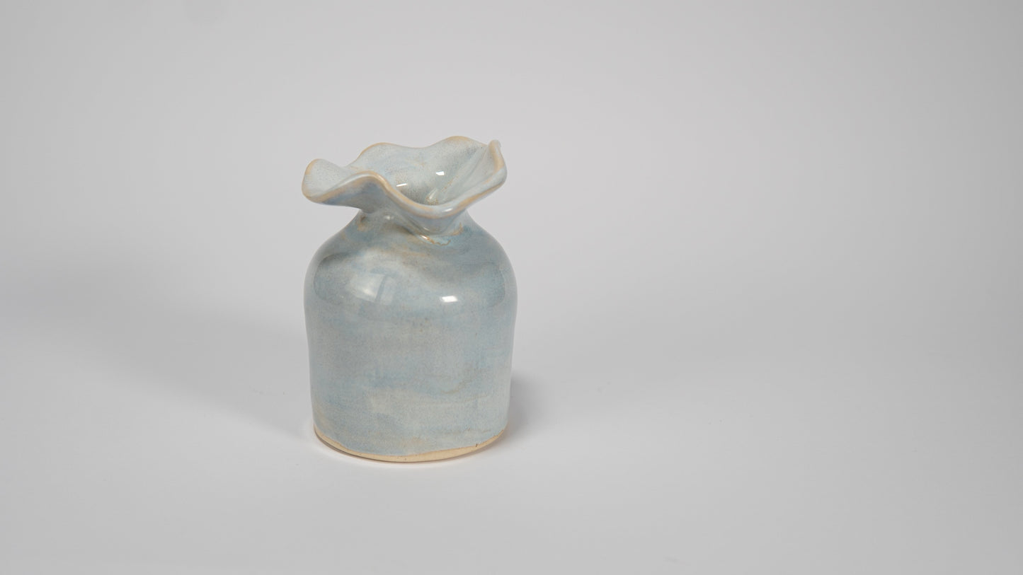 Small ceramic vase with a textured surface on a plain background